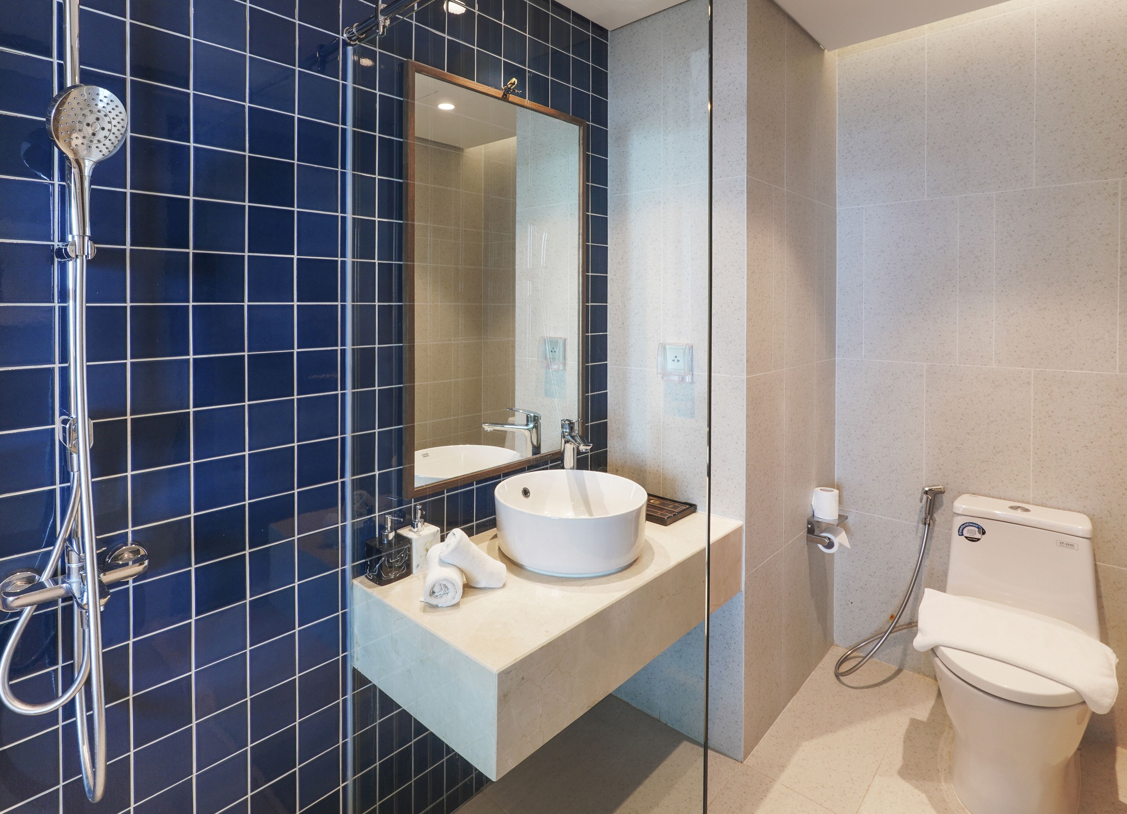 Un bagno moderno con cabina doccia in vetro, lavandino bianco e servizi igienici.