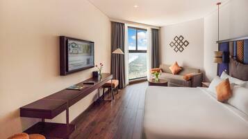 Ein Hotelzimmer mit Bett, einer Couch, einem Schreibtisch und einem Fernseher.
