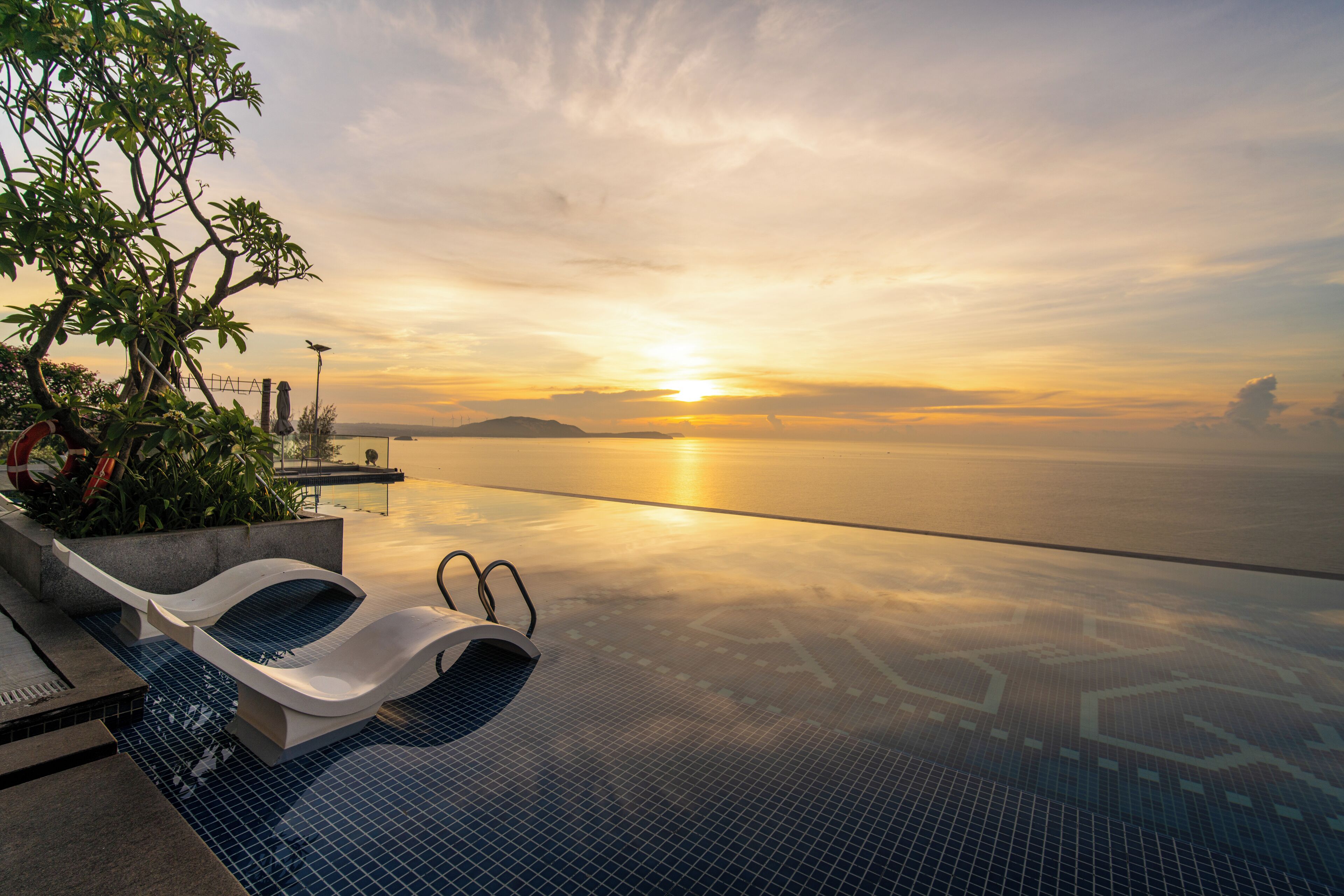 An infinity pool with a view of the sunset over the water.