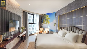 Una habitación de hotel moderna con una cama grande, un televisor montado en la pared, un escritorio con una silla y vistas a palmeras a través del ventanal.