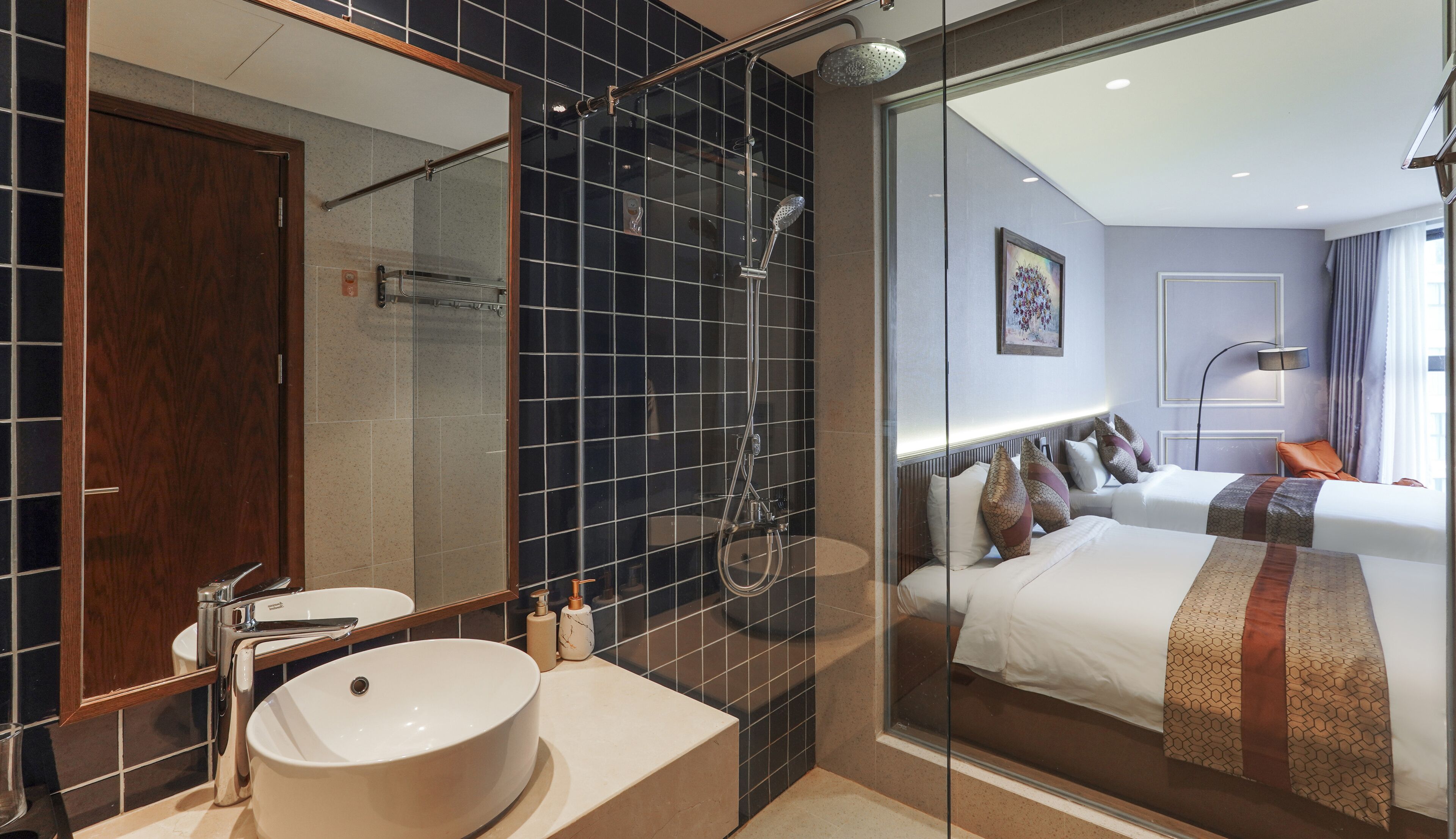 Ein modernes Hotelbad mit einem großen Spiegel, einem runden Waschbecken und einer Duschkabine aus Glas.