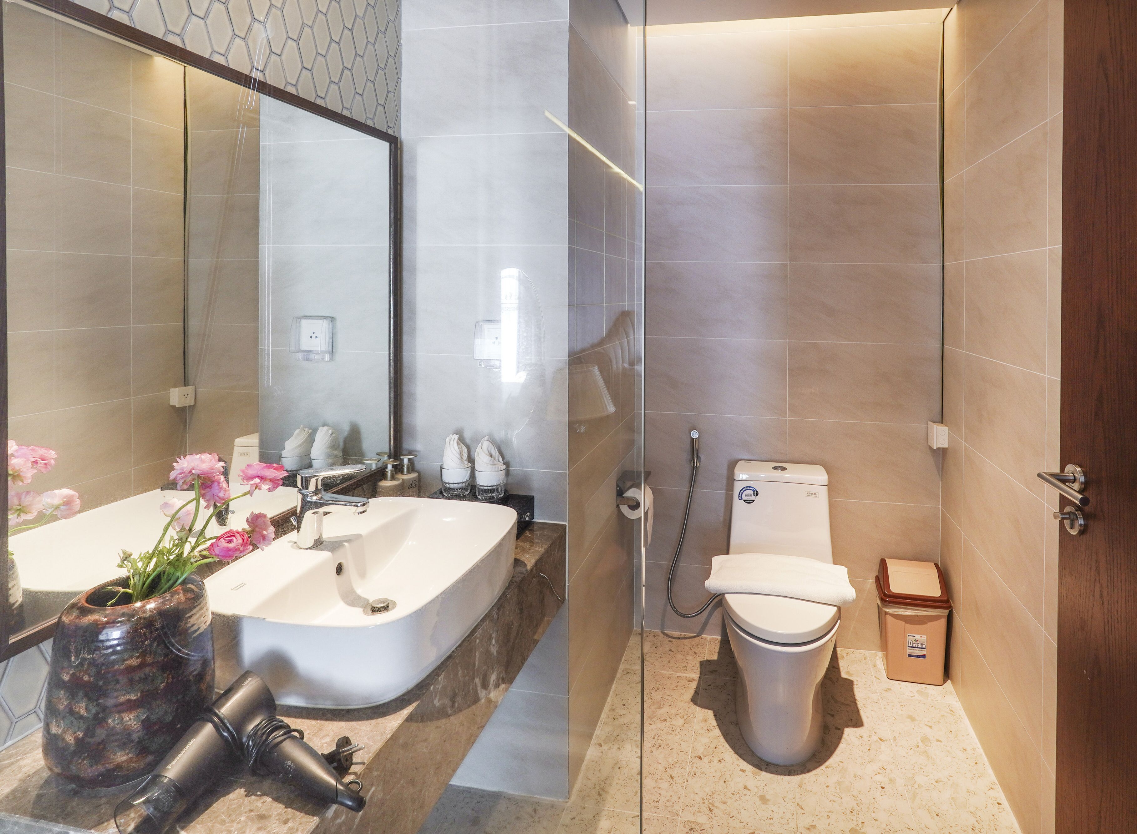 A modern bathroom with a large mirror, dual sinks, a bathtub, a toilet, and a shower area.