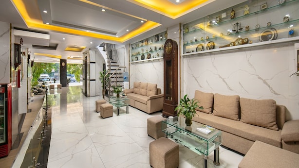 A modern hotel lobby with a marble floor, a glass coffee table, a sofa, and a clock display. - Nhan Hoa Hotel (Hanoi)