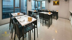 A modern dining area with multiple tables and chairs, large windows, and ceiling lights. - Nhan Hoa Hotel (Hanoi)