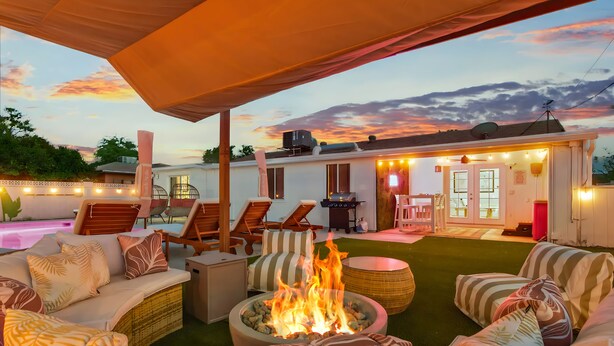 Un patio al aire libre con un brasero, sillas de descanso y una zona de estar cubierta.