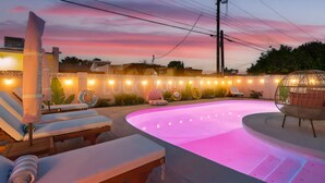 Zona de piscina con sillas de descanso y una pérgola, rodeada por una valla decorativa.