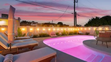 A swimming pool area with lounge chairs and a pergola, surrounded by a decorative fence.