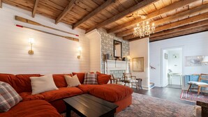 Una sala de estar acogedora con un sofá seccional, una chimenea y una araña.