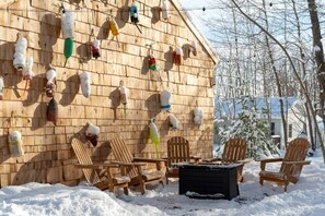 Un bâtiment en bois doté d’une mangeoire à oiseaux fixée au mur et d’un espace extérieur aménagé pour s’asseoir.