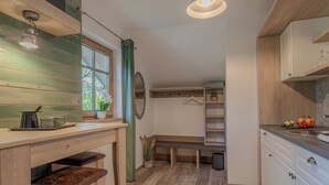 Kompakti keittiö, jossa on puutasot, penkki ja roikkuva kasvi.