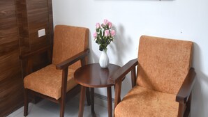 A room with two wooden armchairs and a small round table, a vase with pink flowers, and a mirror on the wall. - Thanh Hang Hotel near Emerald My Dinh (Hanoi)