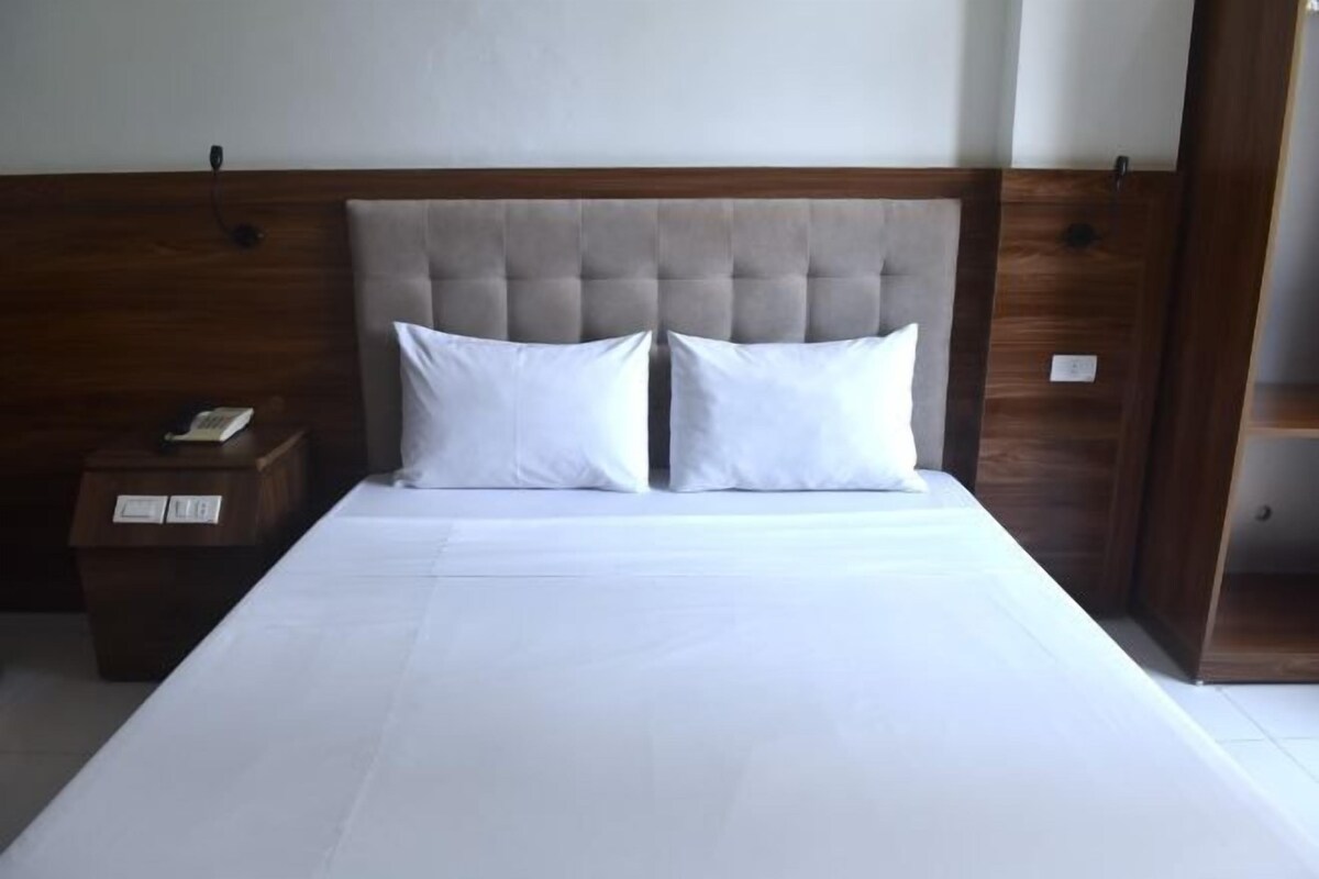A neatly made bed with a tufted headboard, a bedside table with a lamp, and a wooden wardrobe.