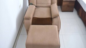A tan massage chair with a control panel, a wooden nightstand with a phone, and a bed with white bedding. - Thanh Hang Hotel near Emerald My Dinh (Hanoi)