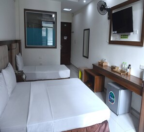 Une chambre d’hôtel avec deux lits, un bureau avec un réfrigérateur, une télévision et une fenêtre donnant sur une piscine.