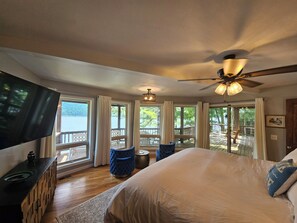 Un dormitorio con una cama grande, televisión y vistas a un muelle y un lago.