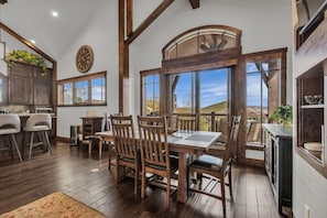 A spacious kitchen with wooden cabinets, a dining area with a large table and chairs, and a view of the outdoors through large windows.