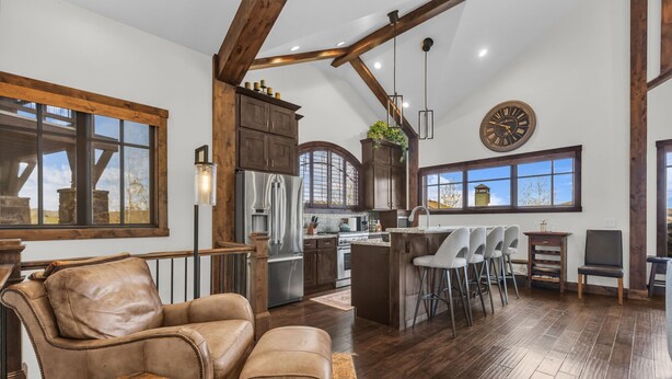 A spacious living area with a leather sofa, a coffee table, and a kitchen with a bar area. - Luxurious 4BD Near Canyons Village (Park City)