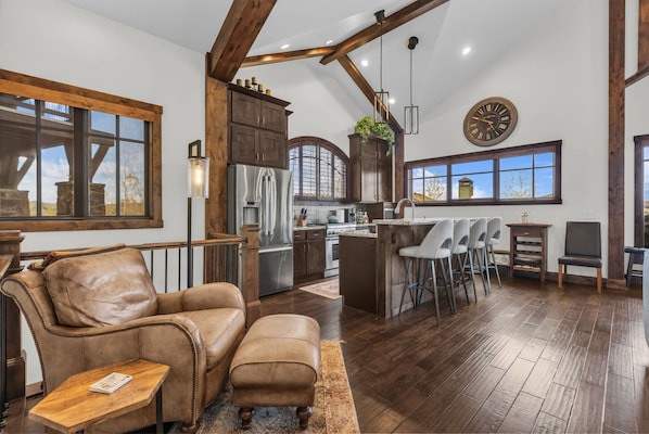 A spacious living area with a leather sofa, a coffee table, and a kitchen with a bar area.