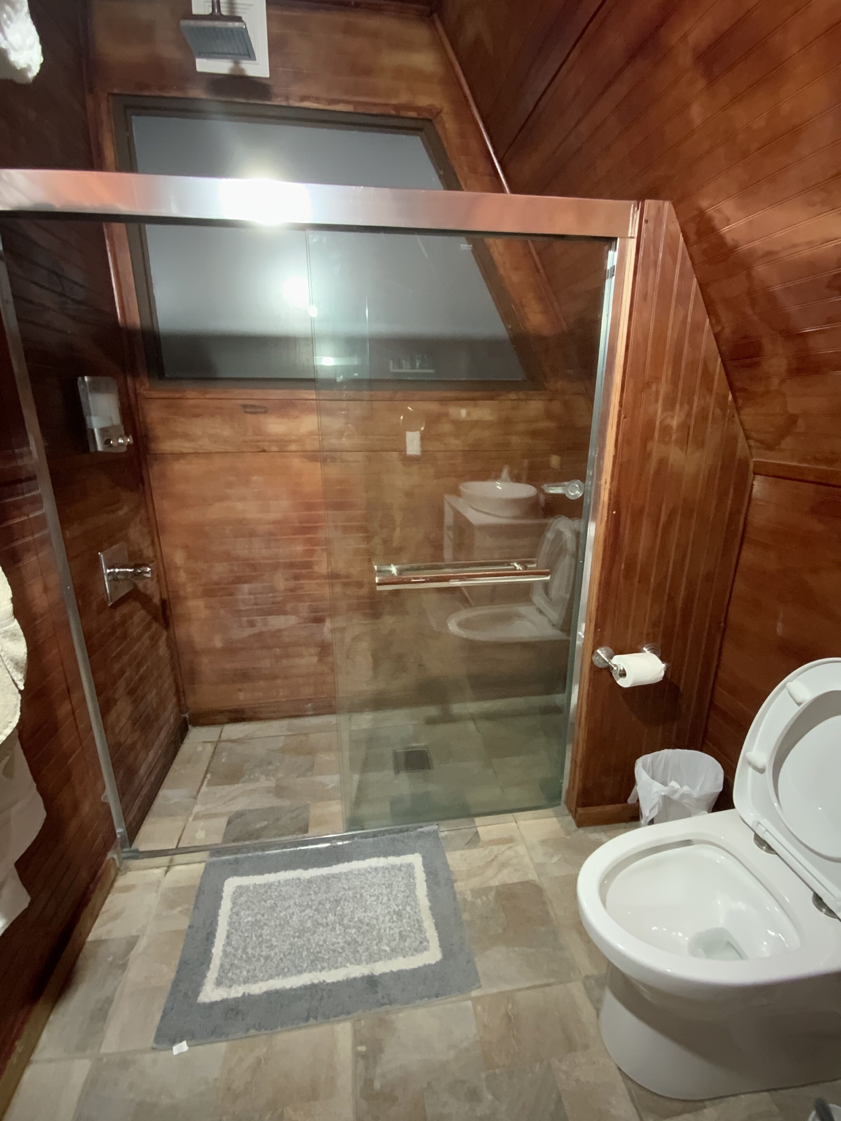 A compact bathroom with a glass-enclosed shower, a toilet, and a sink.