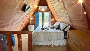 A cozy attic bedroom with a sloped ceiling, a bed with a striped bedspread, a dresser, and a window with curtains. - Cabaña 787
Scape from reality in a cozy cabin
steps to a geological place. (Lares)