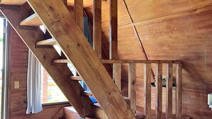 A wooden staircase leading to an upper level, a gray sofa with a blue pillow, and a wooden cabinet. - Cabaña 787
Scape from reality in a cozy cabin
steps to a geological place. (Lares)