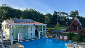 A swimming pool with a covered area, a small building with a glass door, and a wooden cabin in a natural setting. - Cabaña 787
Scape from reality in a cozy cabin
steps to a geological place. (Lares)