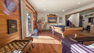 Una habitación acogedora con mesa de billar, banco de madera y tablero de ajedrez.