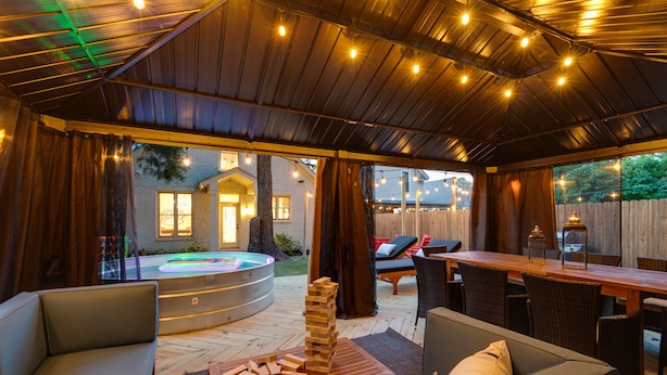 Ein Außenbereich mit Patio, einem Holztisch, Liegestühlen und einem Whirlpool.