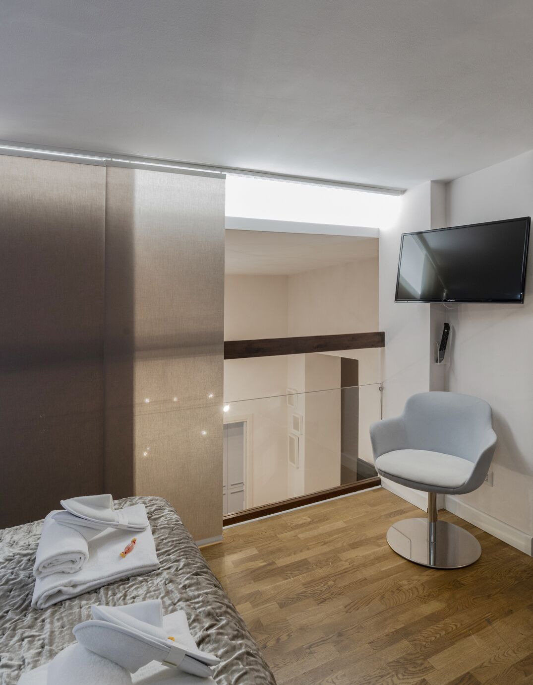 Une chambre d’hôtel avec un lit, une chaise, une télévision et un balcon.