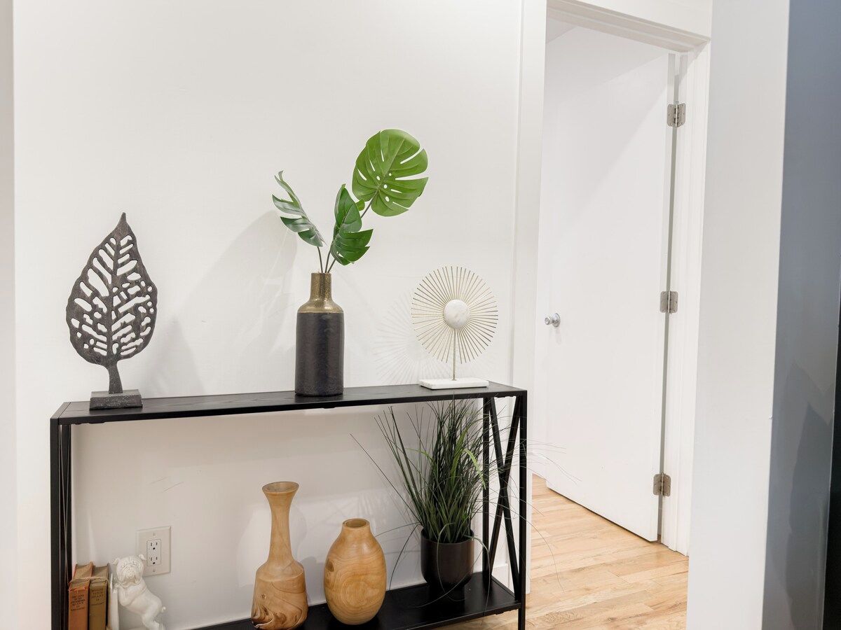 A black console table with decorative items including a leaf sculpture, a potted plant, and a white fan.