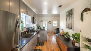 A modern kitchen with stainless steel appliances, grey cabinets, and wooden flooring. - ⁂10min-Airport⁂65"Smart Tv⁂W/D⁂Self Check-In⁂AC⁂DTSA⁂ (Santa Ana)