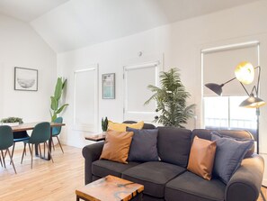Ein modernes Wohnzimmer mit Sofa, Couchtisch und Essbereich.