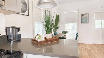 A kitchen with a stainless steel stove, a coffee maker, and a wooden tray with plants and a picture frame.