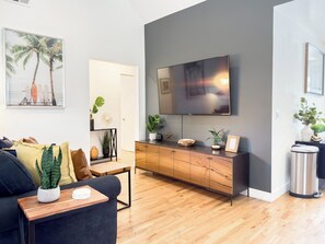 En moderne stue med sofa, sofabord og fjernsyn hængt på væggen.