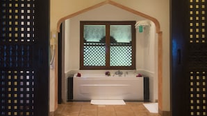 A bathroom with a bathtub, a window with a decorative screen, and a towel rack. - Amani Beach Resort (Kutani)