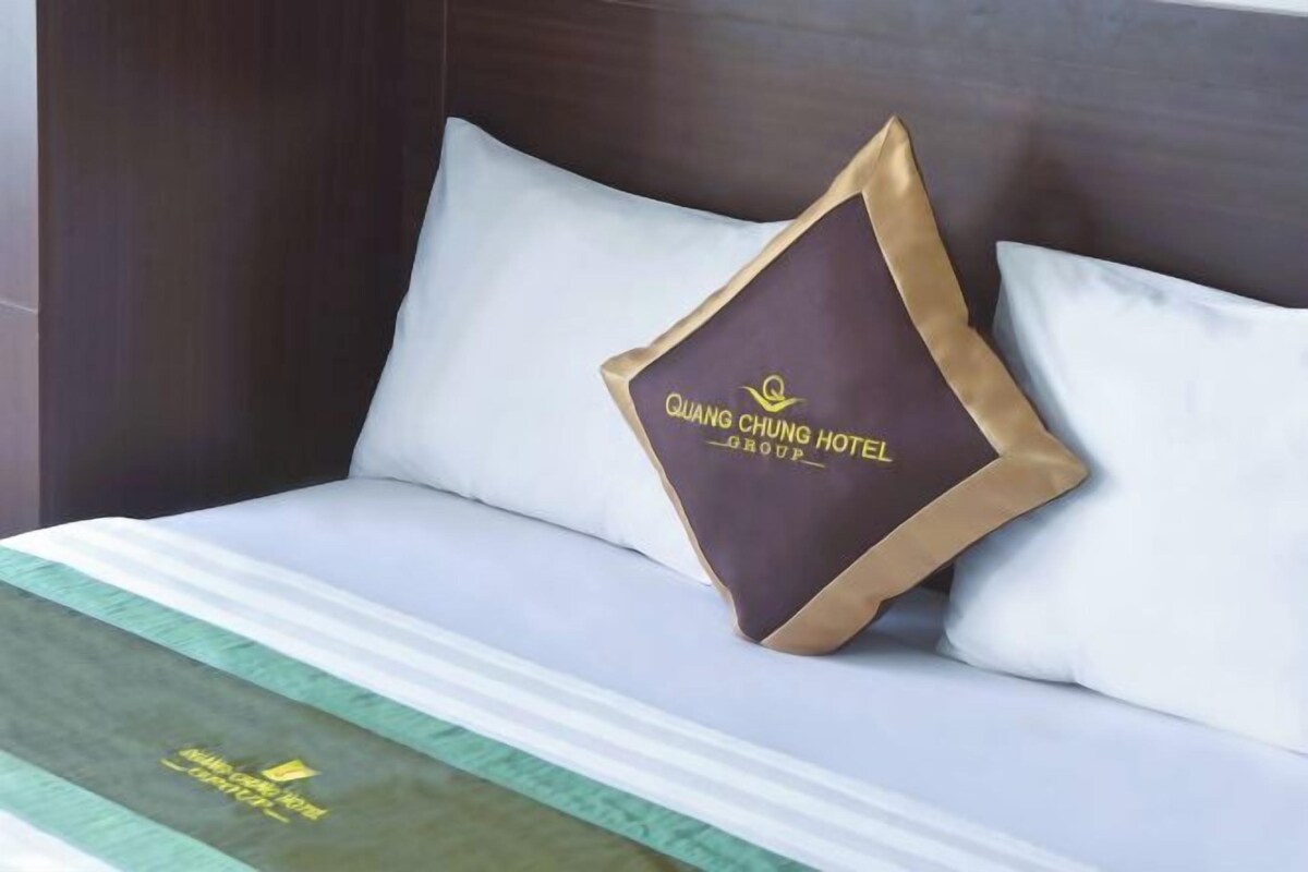 Un llit amb una almoineda que té el text "QUANG CHUNG HOTEL GROUP".