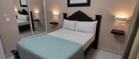 Une chambre à coucher avec un lit, des lampes de chevet, un miroir et un tableau encadré au mur.