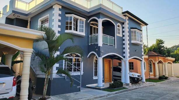 A multi-story residential building with a balcony, large windows, and a staircase leading to the entrance. - Modern 2 Bedroom Apartment 5b in Puerto Plata (Puerto Plata)