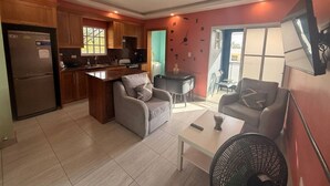 A modern kitchen with wooden cabinets, a refrigerator, and a dining area with a table and chairs. - Modern 2 Bedroom Apartment 5b in Puerto Plata (Puerto Plata)