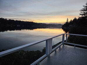 Un lac paisible au coucher du soleil, avec une terrasse en bois et une balustrade.