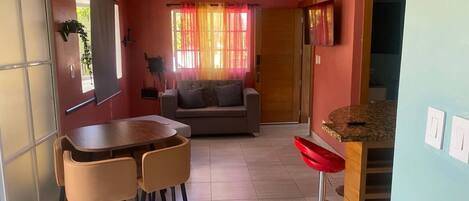 A compact living space with a dining area, sofa, and a small kitchen area.