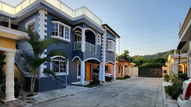 Une maison à deux étages avec une allée et une entrée fermée par un portail.