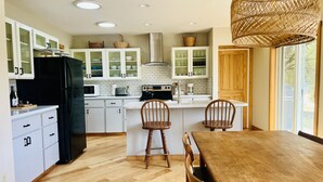 Una cucina moderna con mobili bianchi, un frigorifero nero e un tavolo da pranzo in legno con sedie.