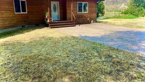 Una casa in legno con un portico, un camino e vista su un paesaggio collinare.
