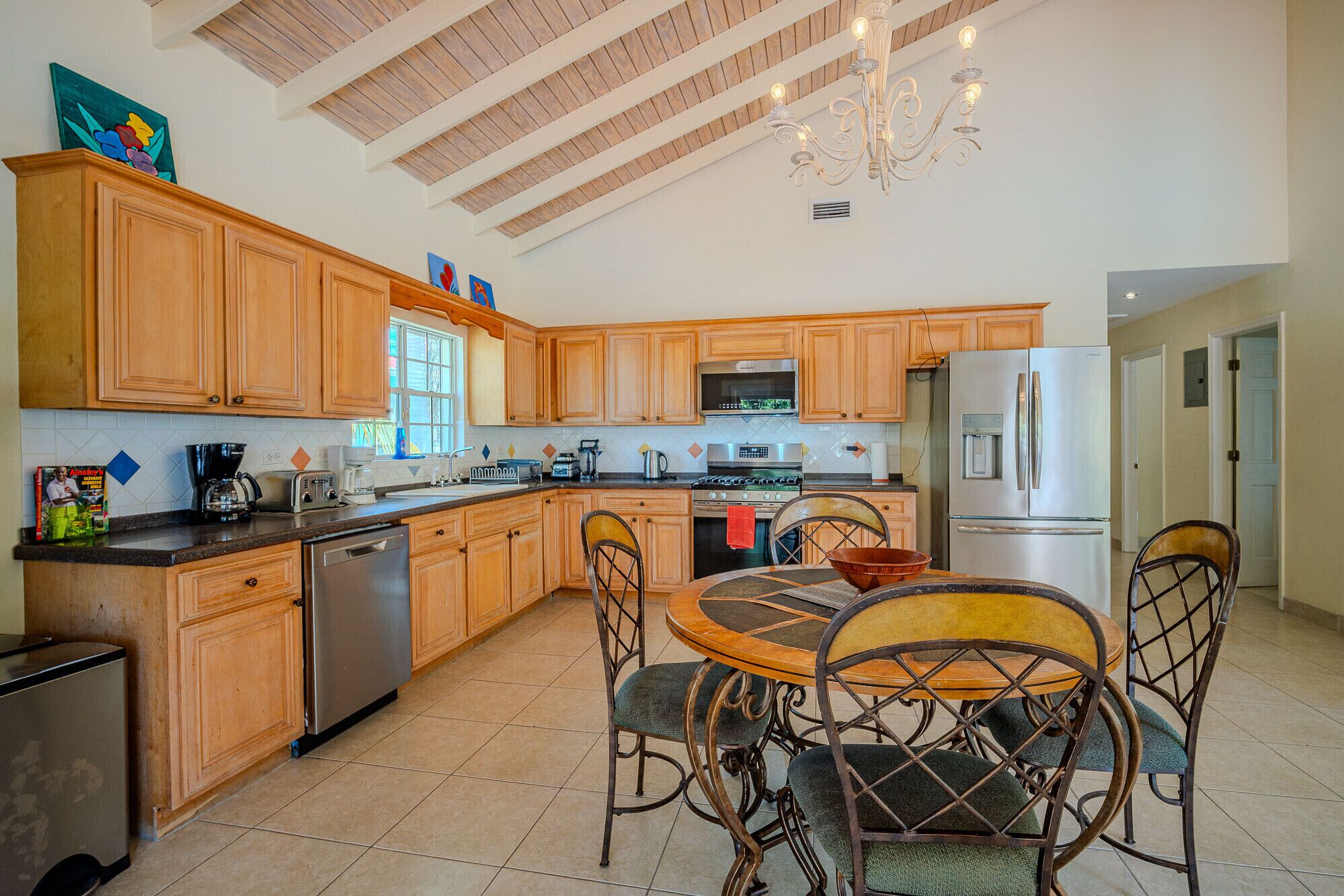 A spacious kitchen with wooden cabinets, a stainless steel refrigerator, and a dining area with a round table and chairs.
