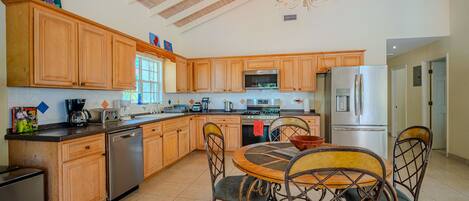A spacious kitchen with wooden cabinets, a stainless steel refrigerator, and a dining area with a round table and chairs.