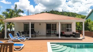 Un espace extérieur abrité comprenant une piscine, des chaises longues et un coin salon avec un canapé et une table basse.