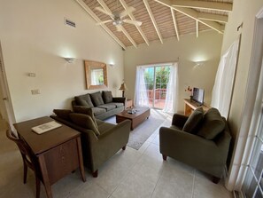 A living room with a sofa, chairs, a coffee table, a TV, and a ceiling fan. - Tropical Caribbean Oasis (Jolly Harbour)