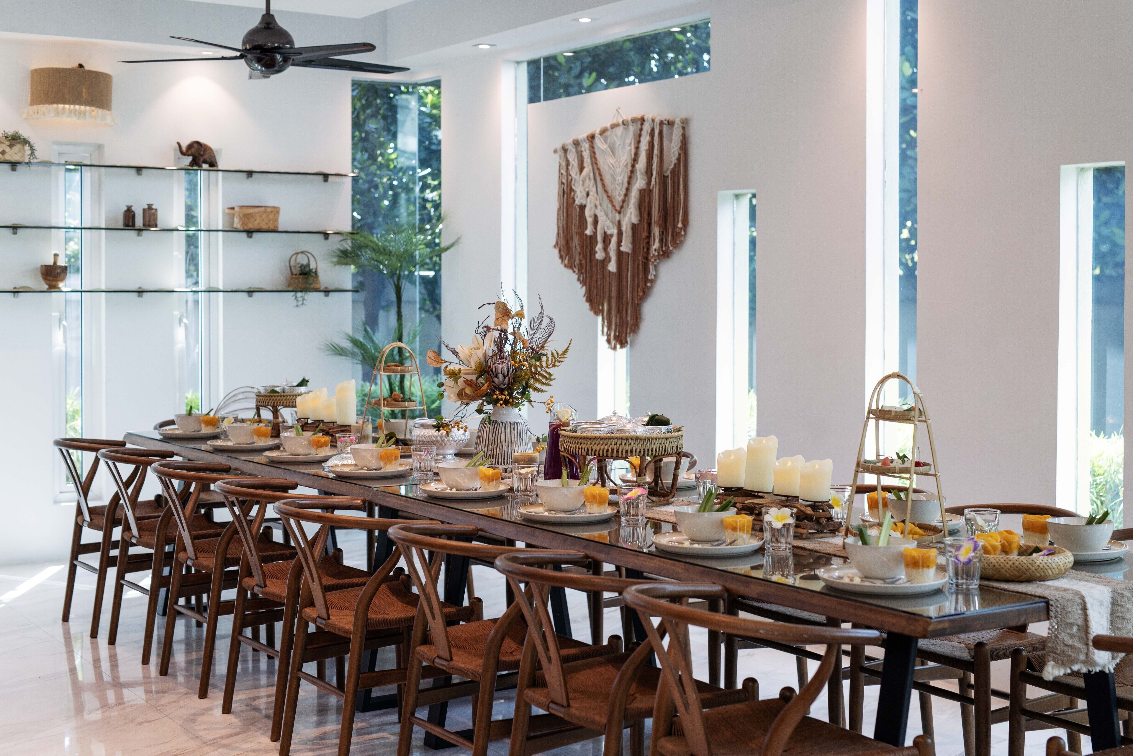 A dining area with a long table set for a meal, surrounded by wooden chairs.