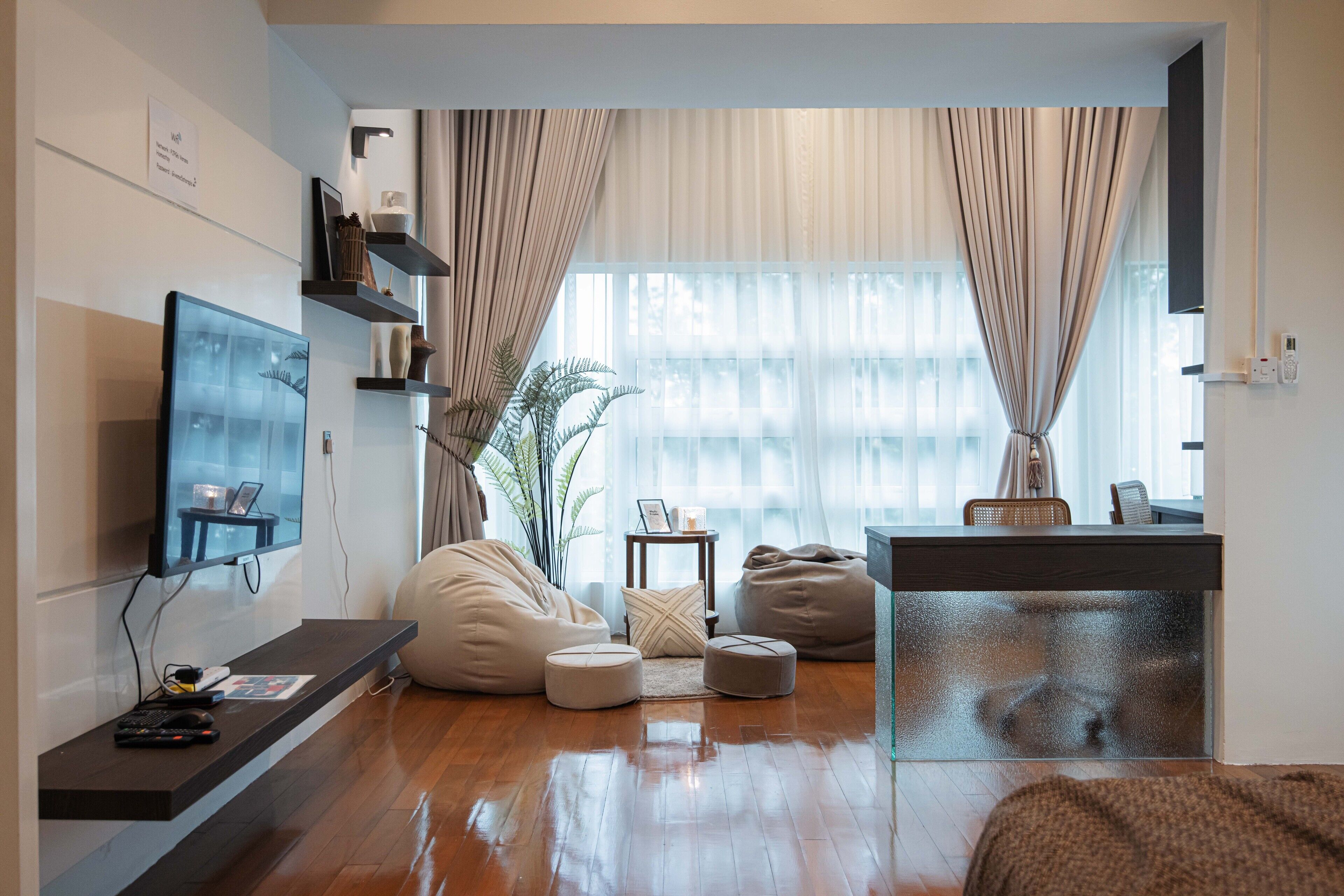 A modern living room with a flat-screen TV, bean bags, a coffee table, and a desk with a chair.
